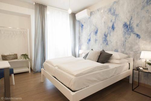 Sleep In Udine في أوديني: غرفة نوم مع سرير أبيض مع لوحة زرقاء على الحائط