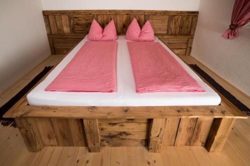 a wooden bed with pink pillows on top of it at Liebe zur Steiermark / Haus Tyrol in Jagerberg
