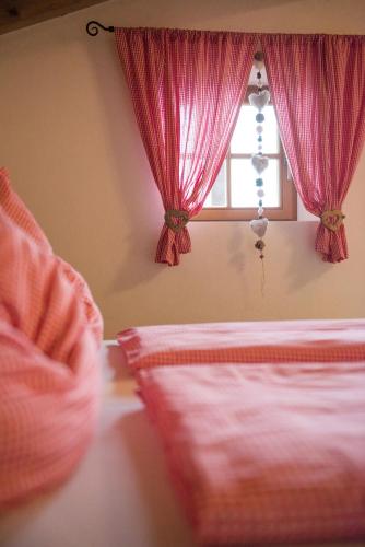 a bedroom with a bed with pink curtains and a window at Liebe zur Steiermark / Haus Tyrol in Jagerberg