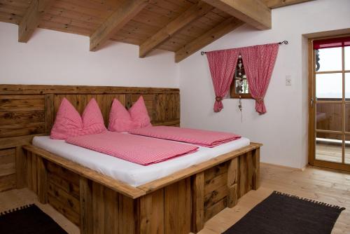 a bedroom with a wooden bed with pink pillows at Liebe zur Steiermark / Haus Tyrol in Jagerberg