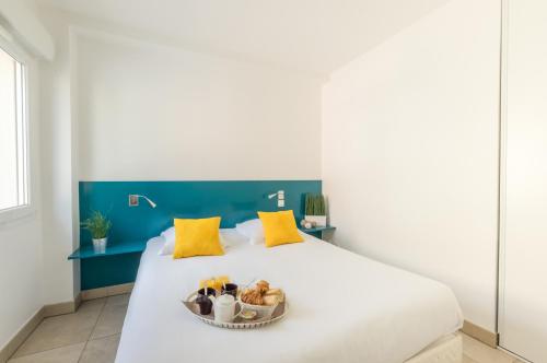 a white bed with a bowl of food on it at Résidence Thalacap in Cap d'Agde