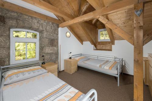 two beds in a room with wooden ceilings and windows at Penzion Solaris in Janov nad Nisou