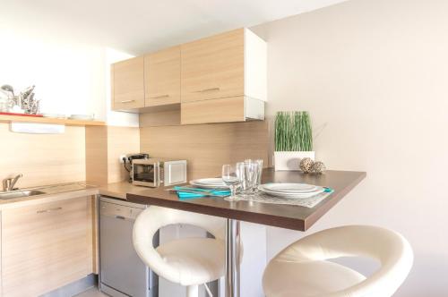a kitchen with two white chairs and a counter with a microwave at Résidence Thalacap in Cap d'Agde