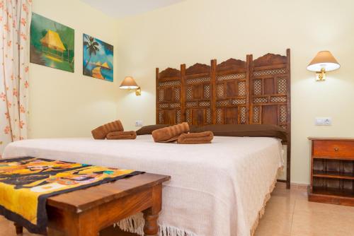 una camera da letto con due letti e una testiera in legno di El Jasmine a Corralejo