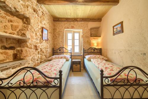 a bedroom with two beds in a stone wall at Villa Stone Queen in Malinska
