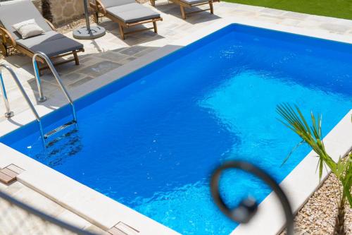 a large blue swimming pool with two chairs next to it at Villa Stone Queen in Malinska