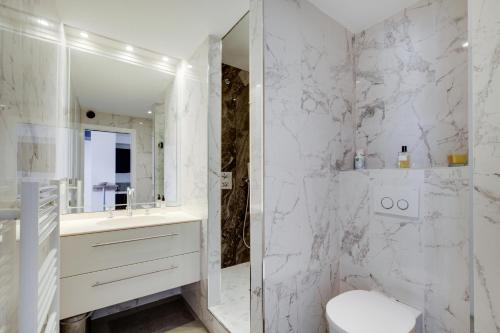 La salle de bains blanche est pourvue de toilettes et d'un miroir. dans l'établissement La Maioneta Carré d'Or, à Nice