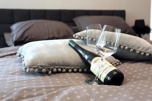 a bottle of wine and two glasses on a bed at Studio apartman Ana in Osijek