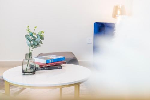 a table with books and a vase with flowers on it at Sanya Sun Seaview Apartment in Sanya