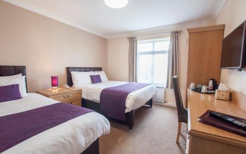 a hotel room with two beds and a desk at Exeter Court Hotel in Exeter