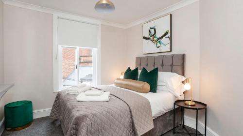 a bedroom with a bed with green pillows and a window at Stylish and most central 2 bed City Centre Apartment in York