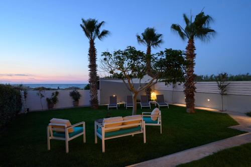 a backyard with a table and chairs and palm trees at Sea La Vie in Adelianos Kampos