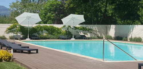 een zwembad met twee parasols en stoelen en een zwembad bij Hotel Balneario De Alceda in Alceda