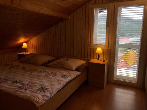 a bedroom with a bed with two lamps and two windows at Villa Danmarie in Vinišće