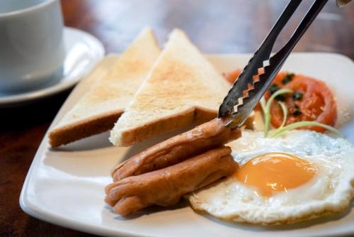a plate of breakfast food with eggs sausage and toast at The Capsule Malioboro in Yogyakarta
