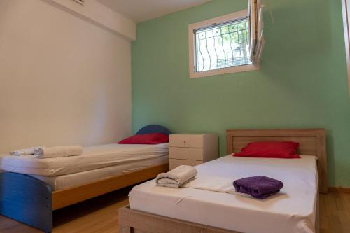 two beds in a room with green walls and a window at Starfish Villa in Iraklitsa