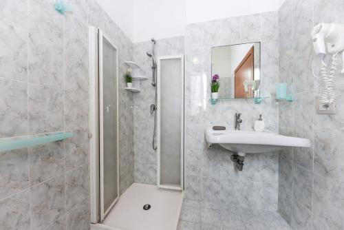 uma casa de banho com um chuveiro e um lavatório. em Hotel Miramare em Marotta