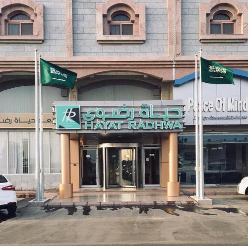 un edificio con dos banderas verdes delante de él en Hayat Redwa Hotel, en Yanbu