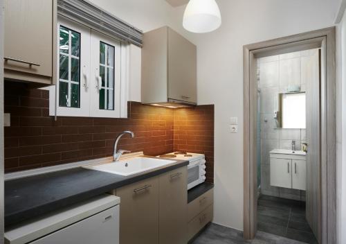 a kitchen with white cabinets and a sink and a mirror at Irene Studios in Pefki