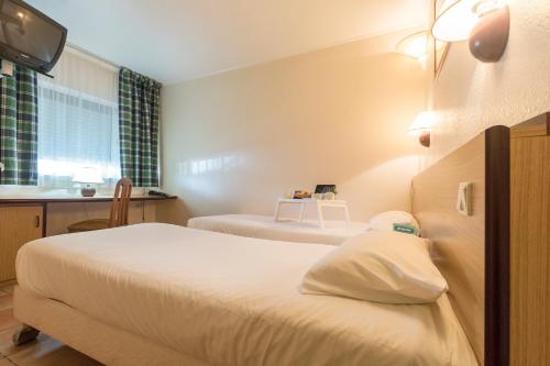 a hotel room with two beds and a television at Campanile Setubal in Setúbal