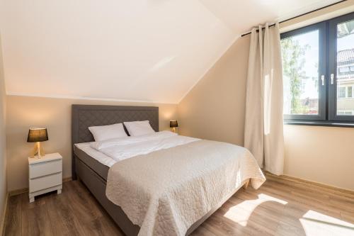 a bedroom with a bed and a large window at Apartamenty Parkowa 13 in Darlowko
