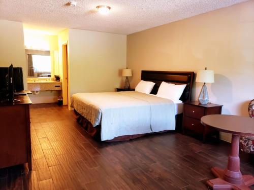 1 dormitorio con cama, mesa y TV en Motel 103 en Calhoun