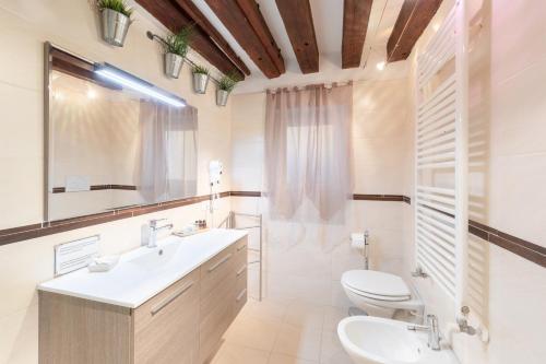 Ca' del Carro Family Apartment في البندقية: حمام مع حوض ومرحاض ومرآة