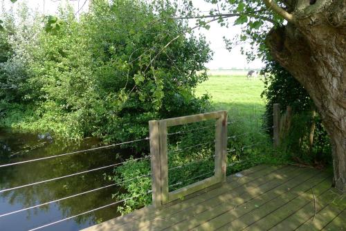 a wooden boardwalk under a tree with a fence at Holiday Home Bonjour Clara in Alveringem