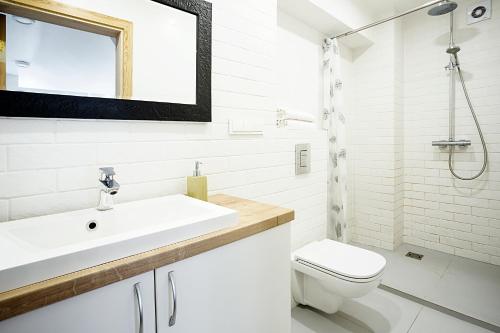 a white bathroom with a sink and a toilet at Baron's Arthouse Apartment in Vilnius