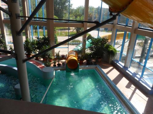 an indoor pool with a water slide in a building at Apartman Garden in Cserkeszőlő