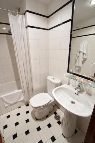 a white bathroom with a toilet and a sink at Pension Monteverde in Cangas de Onís