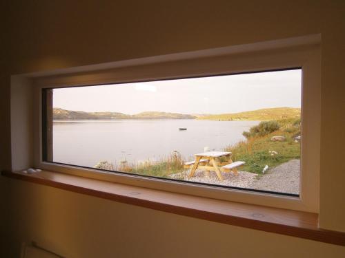 a window in a room with a table and a lake at Otter Bunkhouse in Cairisiadar