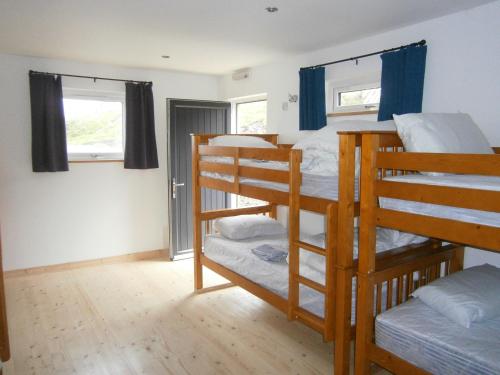 a room with two bunk beds and two windows at Otter Bunkhouse in Cairisiadar