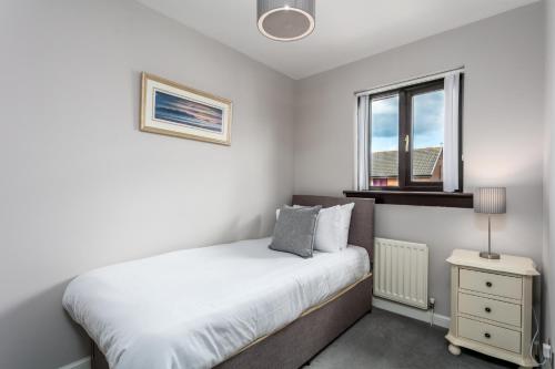 a white bedroom with a bed and a window at The Huntington - Donnini Apartments in Ayr