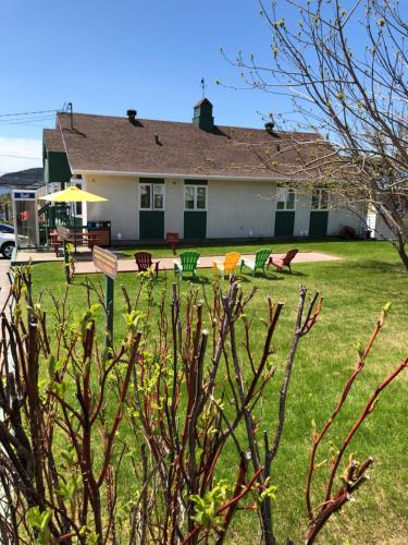 a house with a yard with chairs and a table at Hotel Le Pionnier in Tadoussac