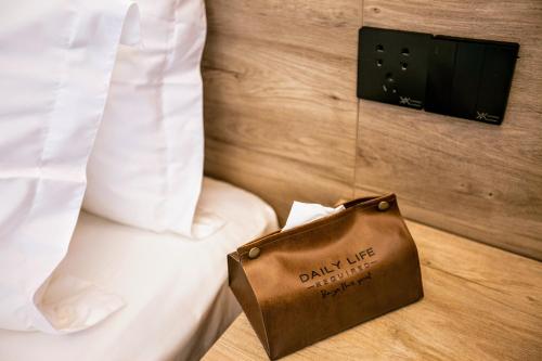 a brown bag sitting on a bed next to a pillow at National Forest Park(Yangjiajie ) MINI Inn in Zhangjiajie