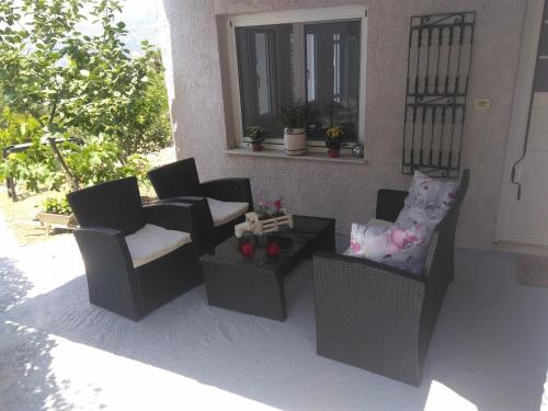 a patio with two chairs and a coffee table at House with fruit trees, olive trees, and sea view. in Vathý
