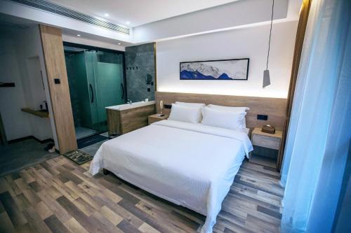 a bedroom with a white bed and a bathroom at National Forest Park(Yangjiajie ) MINI Inn in Zhangjiajie