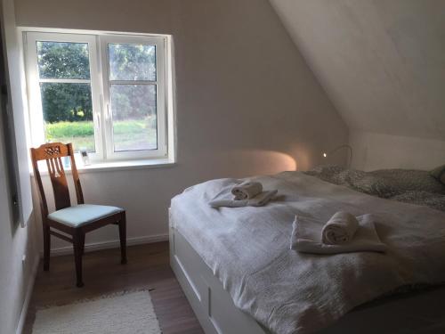 a bedroom with a bed and a chair and a window at Charmantes Haus mit zwei Ferienwohnungen und großem Garten in Aventoft - Enjoy! in Aventoft