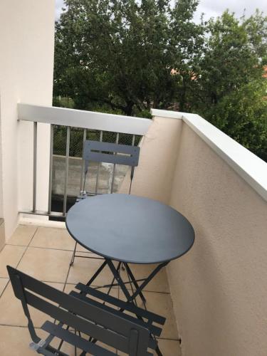 une table et une chaise assises sur un balcon dans l'établissement Résidence d’Artagnan, à Royan
