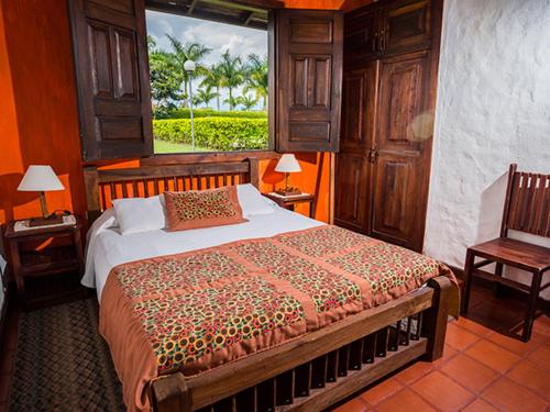 a bedroom with a large bed and a window at Finca Rionegro Rancho La Soledad in Montenegro