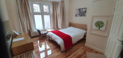 a bedroom with a bed and a desk and a window at Chatsworth Guest House in London