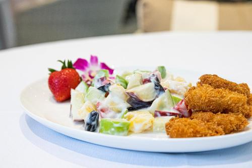 a plate of food with a salad and a strawberry at Patong Heights in Patong Beach