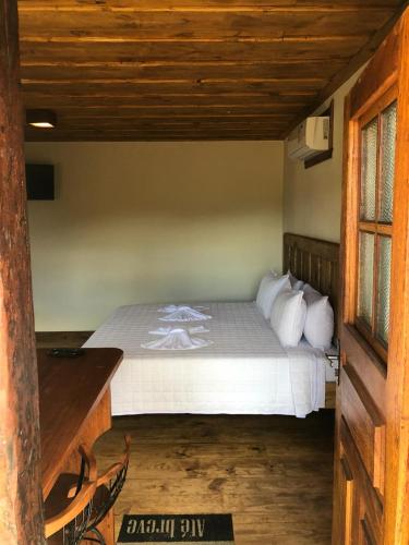 a bedroom with a bed with white sheets and pillows at Pé da Serra Suítes in Lavras Novas