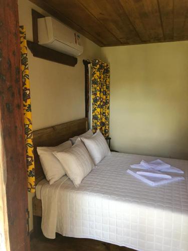 a bed with white sheets and pillows in a room at Pé da Serra Suítes in Lavras Novas