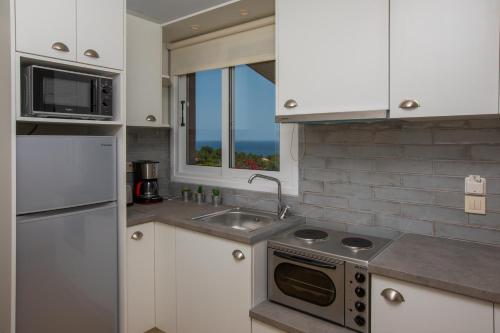 a kitchen with white cabinets and a sink and a window at THALASSA VIEW RESIDENCE in Argostoli