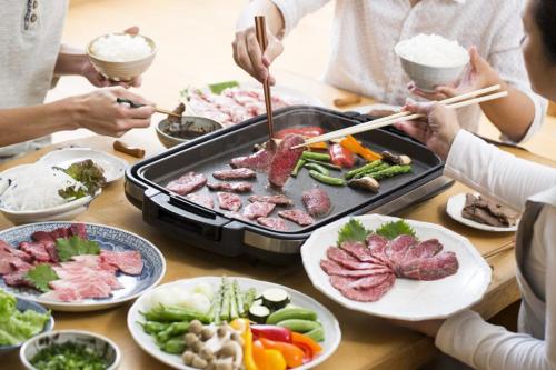 un grupo de personas sentadas alrededor de una mesa con comida en AnBeeeNa, en Akita