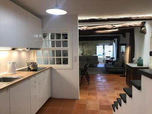a kitchen with white cabinets and a living room at Casa da Muralha Cerveira in Vila Nova de Cerveira