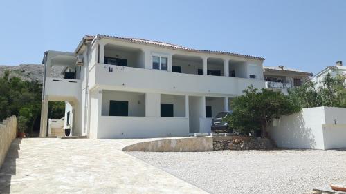 a white house with a car parked in front of it at Apartments Feniks in Pag