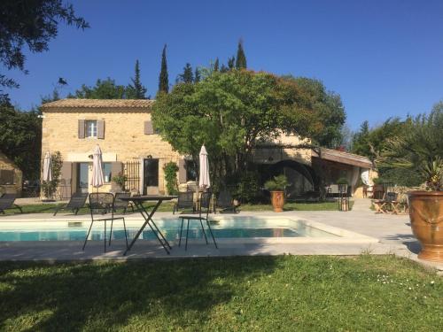 - une piscine avec des chaises et une table en face d'une maison dans l'établissement La Fontaine des Oliviers, à Blauzac